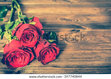 Red roses flowers on wooden background, vintage photo with copy space