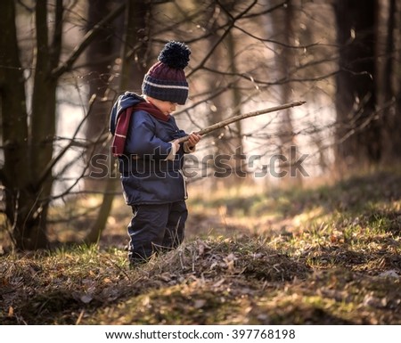 Caucasian boy playing outdoor at springtime. Boy playing with stick found in the forest Royalty-Free Stock Photo #397768198