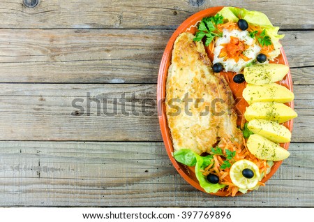 Catfish filet with boiled potatoes on the old wooden background, food menu 