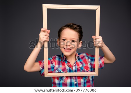 Portrait of positive smiling little boy holding frame