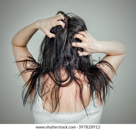 Woman running her fingers through her hair scratching the back of her head.