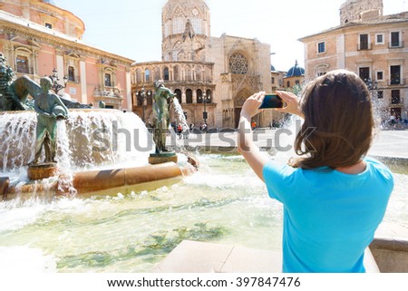 Tourist taking travel picture with phone of Cathedral in Valencia, summer holidays. Unrecognizable female young adult enjoying Spanish vacations in blue t-shirt.