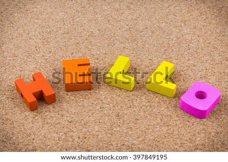 Colorful wooden English alphabets hello on brown cork wood  background