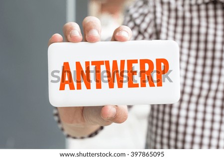Man hand showing ANTWERP word phone with  blur business man wearing plaid shirt. 