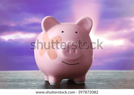Piggy Bank with adhesive bandage wooden table, on sunset background