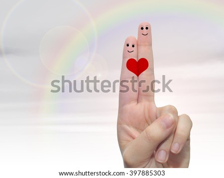 Concept or conceptual human or female hands with two fingers painted with a red heart and smiley faces over rainbow sky background for valentine, romantic, love, couple, young, family or wedding