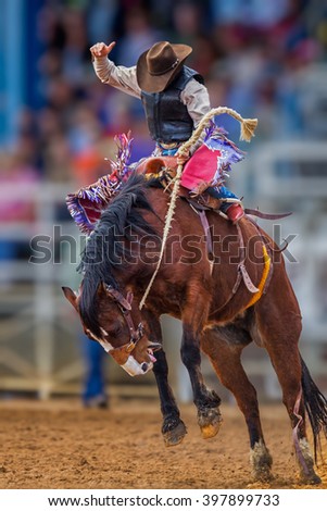 Mystery cowboy bucks on wild mustang in Florida Rodeo Royalty-Free Stock Photo #397899733