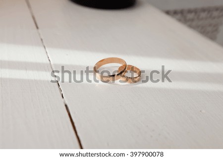 Gold wedding rings on a white table in the sun