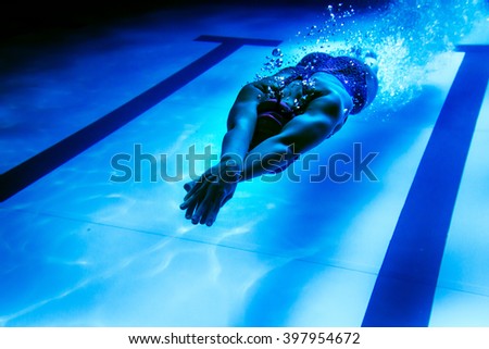 Female swimmer underwater/ Underwater shot of a swimmer diving after the jump in the swimming pool.  Royalty-Free Stock Photo #397954672