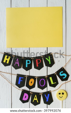 Happy fools day black banner colorful lettering on white barn wood rustic planks background. April greeting postcard template. Space for text, copy.