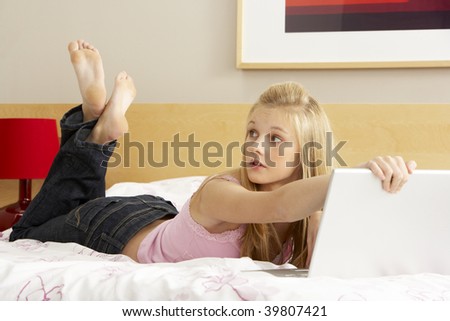 Guilty Teenage Girl Using Laptop In Bedroom