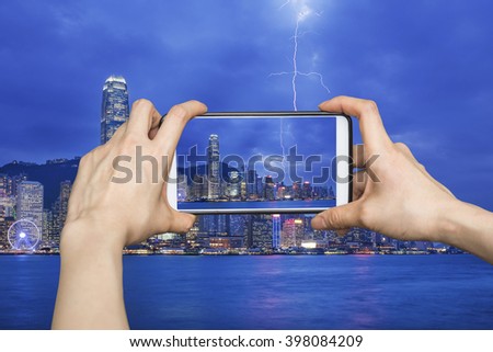 Girl taking pictures on mobile smart phone in Thunderstorm HongKong cityscape at night , Hong kong city.