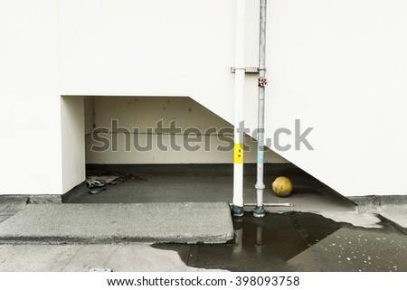 Exterior picture of old white wall,water, ball and water pipe.