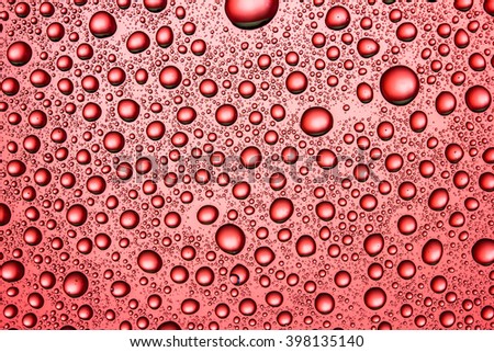 Water drops on red glass surface texture.