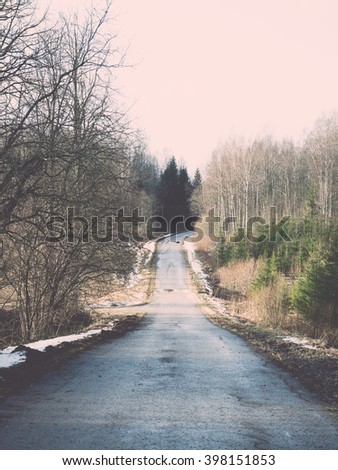empty road in the countryside with trees in surrounding. perspective in winter - vintage film effect