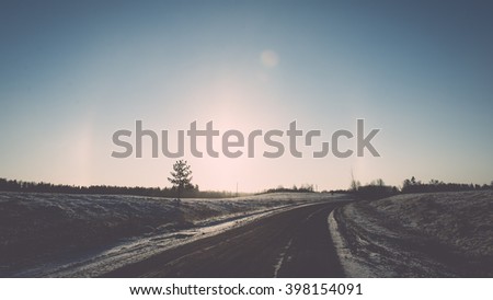 empty road in the countryside with trees in surrounding. perspective in winter - vintage film effect