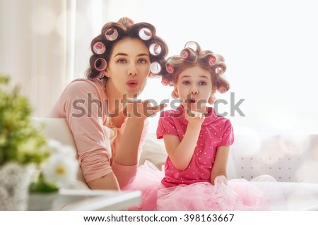 Happy loving family. Mother and daughter are doing hair and having fun. Mother and her child girl playing, kissing and hugging.