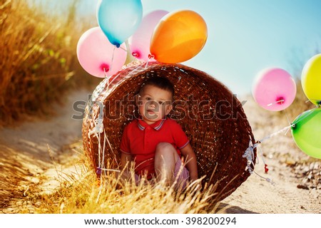 Portrait boy with colorful balloons on yellow field
