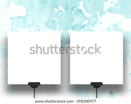 Close-up of two square blank frames supported by clips against aqua abstract background