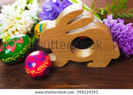beautiful Easter eggs with  flowers hyacinths on a brown wooden background. composition with a wooden figure of a rabbit