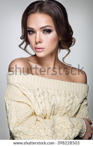 Beautiful woman portrait. Young lady posing in warm sweater. Nice makeup and hairstyle. Studio photo shoot. 