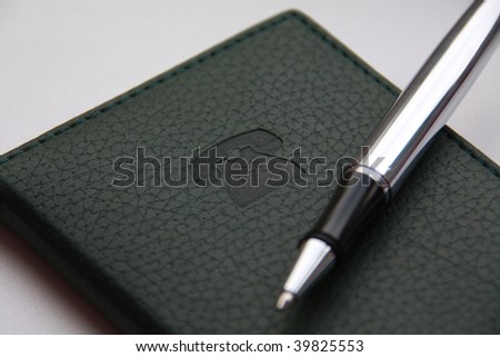 Green notebook with stamping sign of the telephone and ball-point pen