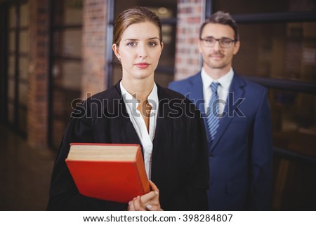 Portrait of confident female lawyer with businessman standing in office
