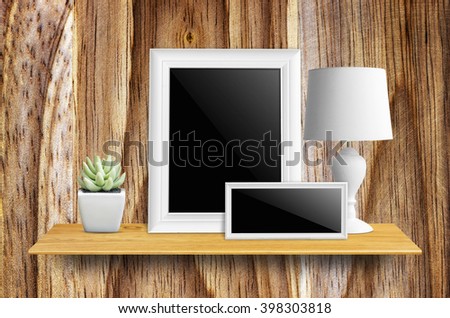 Empty picture frame isolated with clipping path, lamps and potted cactus on bookshelf  - For product display.