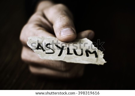 closeup of the hand of a young man with a piece of paper with the word asylum, with a dramatic effect Royalty-Free Stock Photo #398319616