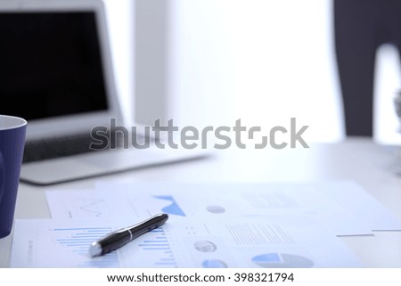 
Office workplace with a laptop and financial documents on the light reflecting table