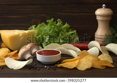 potato chips . sauce ketchup. According to many people, very well with cheese and herbs. Also pictured mushrooms, pepper and spices. All this on a wooden table.