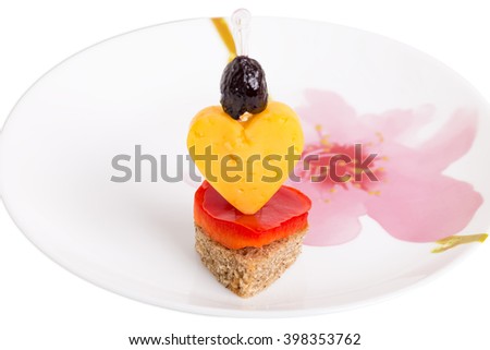 Deliicous sandwich in form of heart with cheese and olive on the plate with floral pattern. Macro. Isolated on a white background.