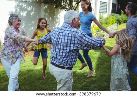 Multi-generation family playing ring around rosie in back yard Royalty-Free Stock Photo #398379679