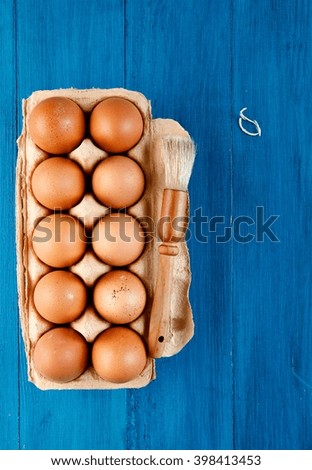 Eggs with brush on blue wooden background