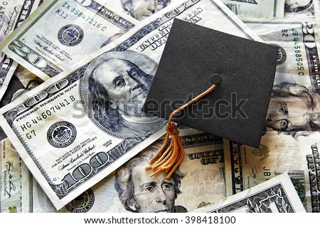 Miniature graduation cap on hundred dollar bills                                Royalty-Free Stock Photo #398418100