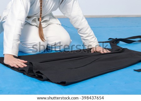 An aikidoka girl folding her hakama for Aikido training Royalty-Free Stock Photo #398437654