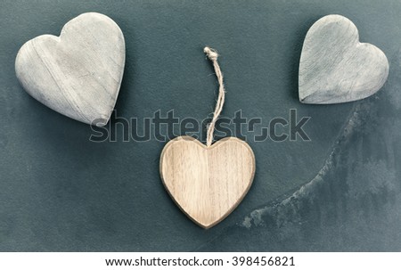 Vintage stylized three wooden hearts on stone background, conceptual picture.