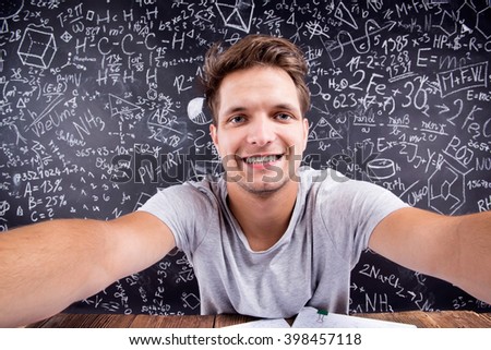 Hipster student doing taking selfie against a big blackboard