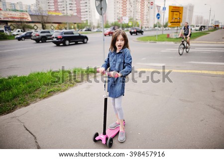 School aged little girl in dress on the scooter in the city street