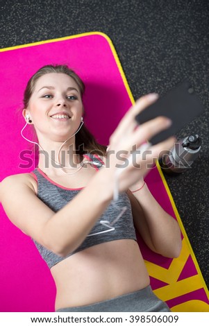young sports woman taking selfie lying on the mate in the gym
