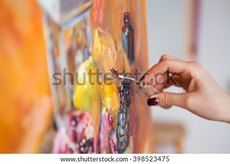 artist paints a picture of oil paint with palette-knife closeup