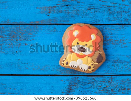 Homemade gingerbread cookie in the shape of orange lion on a wooden background. Space for text and selective focus.