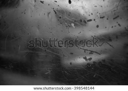 Blurry reflection of a car on old metal grungy surface with rusty scratches and dirty stains. Abstract background. Black and white photo.