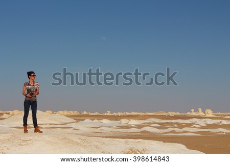 Young beautiful girl takes a picture in the middle of the amazing White desert close to Farafra oasis in Egypt