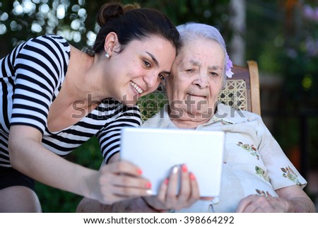 girl take selfie on tablet with old grandma 