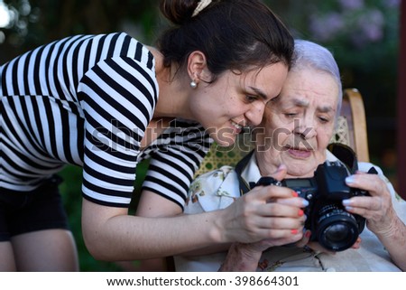 grandma holding digital photo camera with young girl