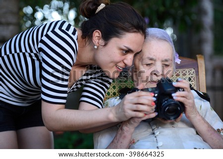 grandma learning photography camera with girl in park