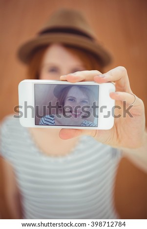 smiling hipster woman taking a selfie against a wooden background