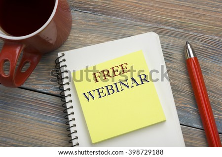 Free Webinar. Notepad With Text On Wooden Table. Office desk table with supplies top view