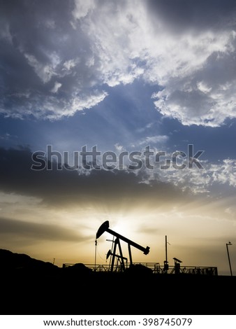 Sunset and silhouette of crude oil pump in oil field.